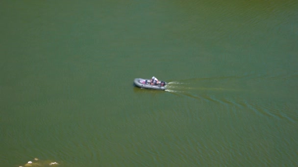 Un homme descend la rivière dans un bateau en caoutchouc avec un moteur — Video