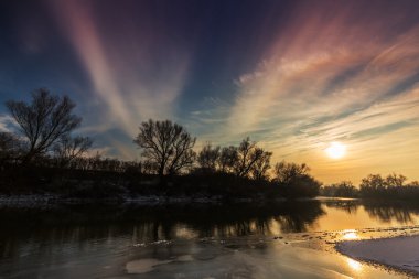 Kapsamındaki Frost ağaçlar ve gün batımında kışın donmuş nehir