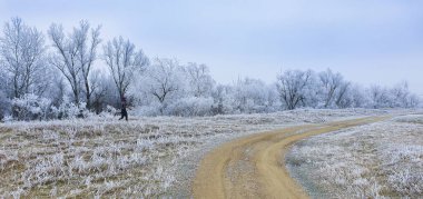 Winter scenery in remote rural area in Europe, with frost covered fields and country road