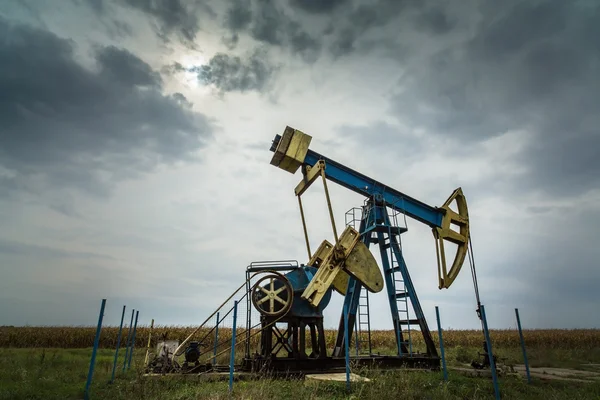 Puits de pétrole et de gaz profilés sur ciel dramatique — Photo