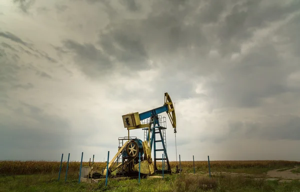 Oil and gas well profiled on dramatic sky — Stock Photo, Image