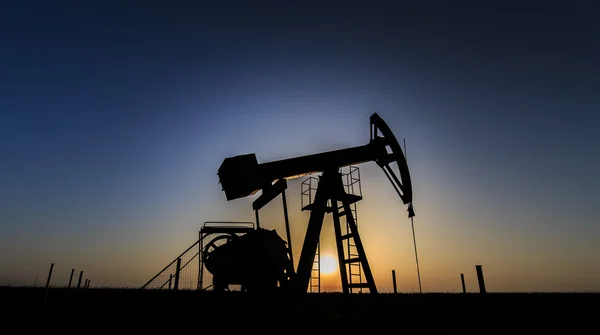 Öl- und Gasbrunnensilhouette in abgelegener ländlicher Gegend lizenzfreie Stockfotos