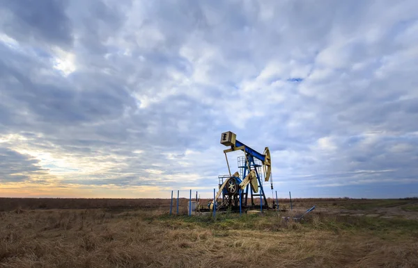 Exploitation d'un puits de pétrole et de gaz profilé sur le ciel couchant — Photo