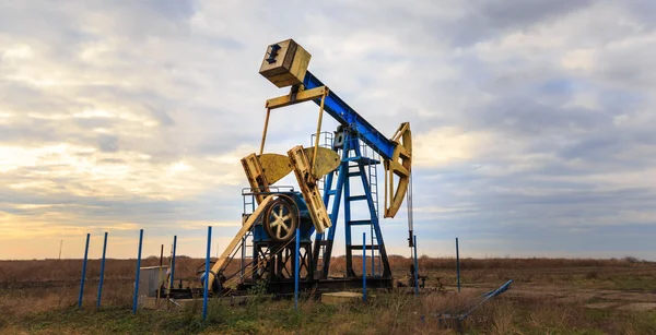 Operación de petróleo y gas bien perfilado en el cielo puesta de sol — Foto de Stock