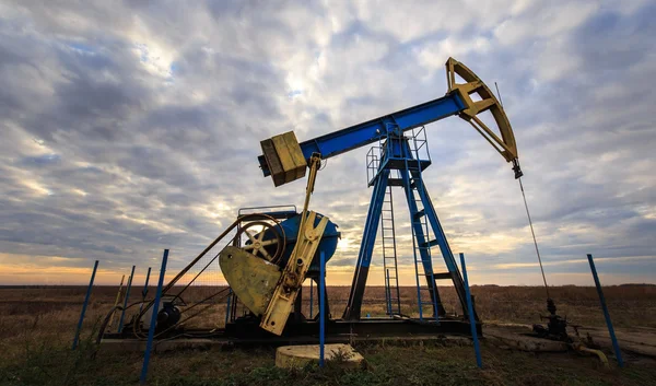 Operación de petróleo y gas bien perfilado en el cielo puesta de sol — Foto de Stock