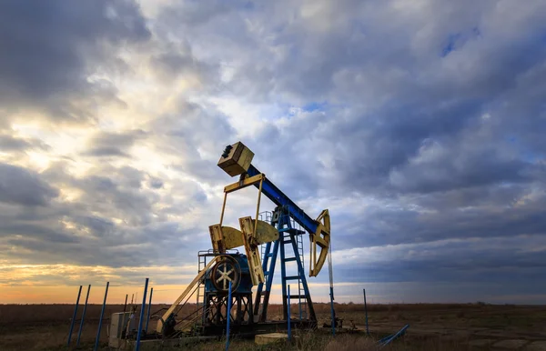 Operating oil and gas well profiled on sunset sky — Stock Photo, Image