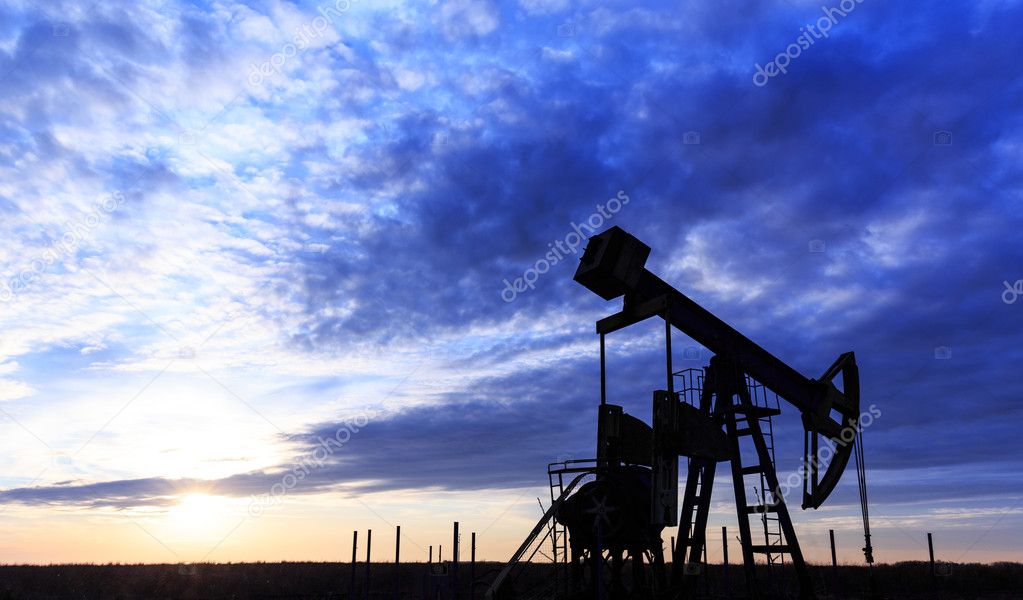 Industrial oil and gas well pump at sunset