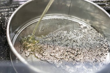 Paslanmaz çelik ızgarada veya yağ yağıyla ızgara yapan sürekli ve otomatik makine tarafından üretildikten sonra bir sürü iğne veya fiş parçası