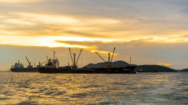 Lojistik ithalat için büyük bir kargo gemisi. Akşamları denize demir atar. Altın gün batımıyla birlikte.