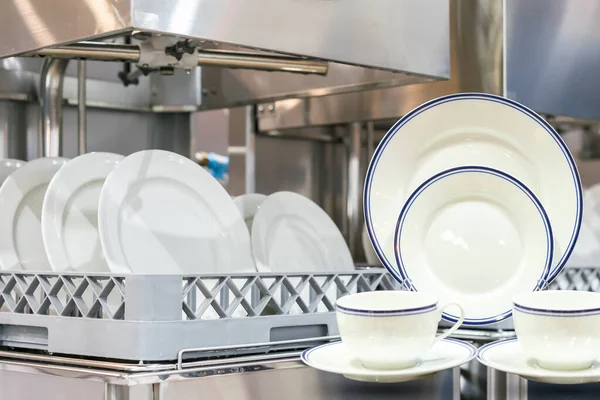 厨房餐厅用自动洗碗机洗碗的盘子杯和篮子上的许多白盘 — 图库照片