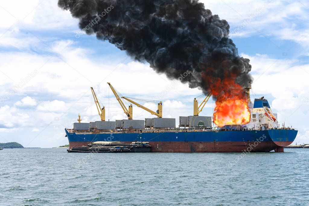 Large general cargo ship for logistic import export goods and other the explosion and had a lot of fire and smoke at sea in bright day