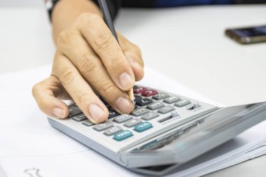 İnsan eli, ofis kavramlarındaki gelir ve giderleri hesaplamak için bir hesap makinesi kullanır 