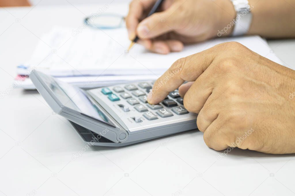 hand of man use a calculator to calculate income and expenses in the office concepts 