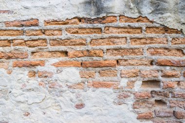 Boş eski tuğla duvar. Zarar görmüş alçılı eski püskü bina.