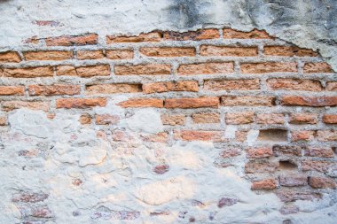 Boş eski tuğla duvar. Zarar görmüş alçılı eski püskü bina.