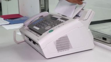 Eleman ofiste faks makinesi kullanıyor. Veri transferi için ekipman.