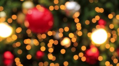 Büyük, güzel dekore edilmiş bir Noel ağacının detaylı bir görüntüsü. Parlak ışıklar, parlak metalik toplar, kırmızı ve altın süsler ve yıldız şeklinde dekorasyonlar. Tatil için mükemmel.