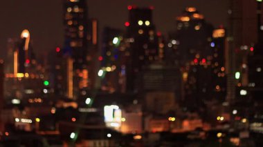 Geceleri yüksek gökdelenlerin soyut görüntüsü. Odaklanamayan pencereler ve tavan lambaları güzel, rüya gibi bir bokeh etkisi yaratıyor. Dairesel, sıcak ışıklar