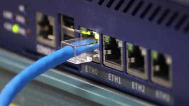Veri transferi ve internet ağ teknolojisi için aktif bağlantı ışıklarını gösteren bir gigabit ağ anahtarına bağlı mavi ethernet kablosunun yakın plan görüntüsü