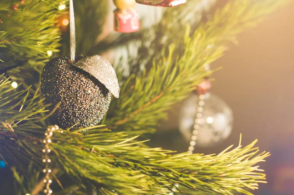 Anno nuovo e giocattolo di Natale in una forma di mela d'argento appesa su un albero di Natale circondato da altri giocattoli — Foto Stock