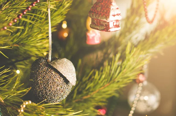 Anno nuovo e giocattolo di Natale in una forma di mela d'argento appesa su un albero di Natale circondato da altri giocattoli — Foto Stock