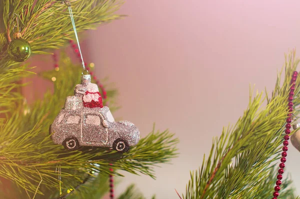 Новорічна та різдвяна іграшка у формі срібного автомобіля з подарунками на даху, що висить на ялинці в оточенні інших іграшок — стокове фото