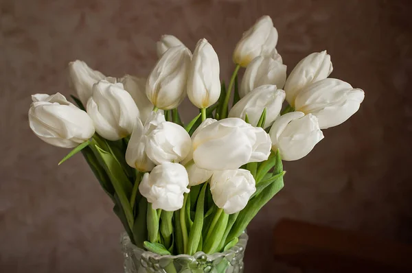 Букет белых тюльпанов в стеклянной вазе дома. — стоковое фото