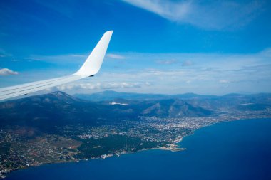 Sonsuz denizin üzerinde uçan uçak kanadı manzarası. Güneşli yaz gününde arka planda kıyı.