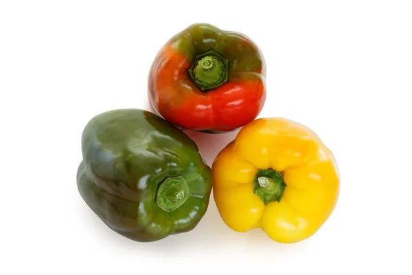 Three bell peppers, green, red and yellow, laying on a flat surface, isolated on white background with a clipping path.
