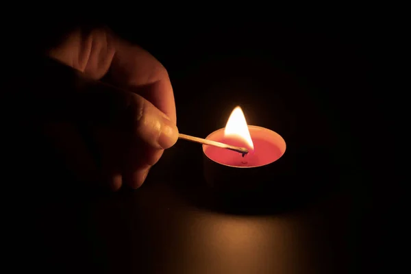 Encender una vela roja con una cerilla en la oscuridad. Concepto de memoria. Fondo negro —  Fotos de Stock