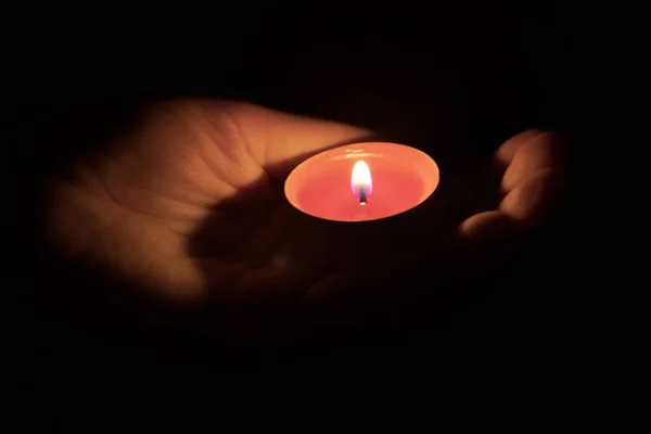 Encender una vela roja en una palma en la oscuridad. De cerca. Concepto de memoria — Foto de Stock