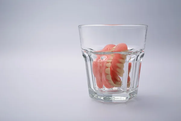 Un conjunto de dentaduras en un vaso de agua — Foto de Stock