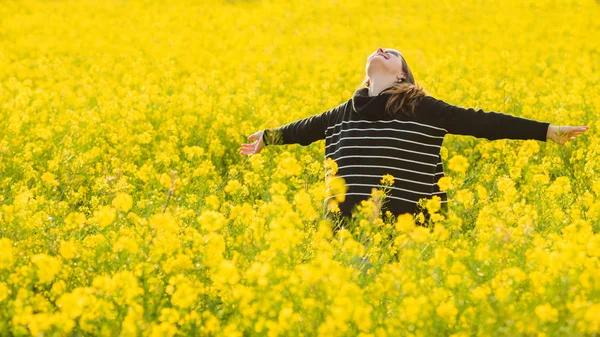 Vrouw in een geel gebloemde veld — Stockfoto