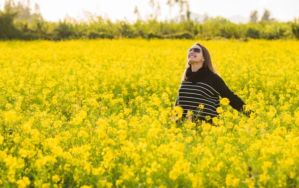 Vrouw in een geel gebloemde veld — Stockfoto