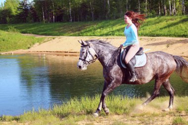 Gri bir atın üstünde hızlı giden genç kız.