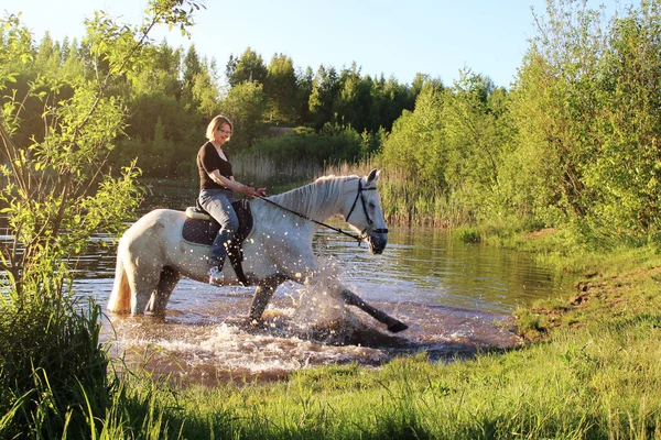 Elderly woman on a white horse in a pond enjoying a beautiful day-Concept of love between people and animals-Horse is a noble animal