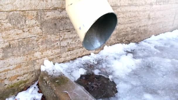 The bottom of a drainpipe with dripping snow melting — Stock Video