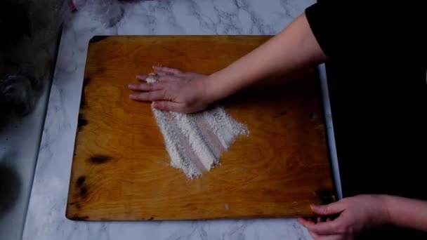 Kvinnliga händer strö mjöl på en paj ombord — Stockvideo