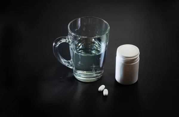 Pills and glass of water on black background — Stock Photo, Image