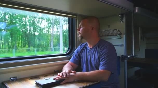 Un hombre cabalga por la ventana en un tren — Vídeo de stock