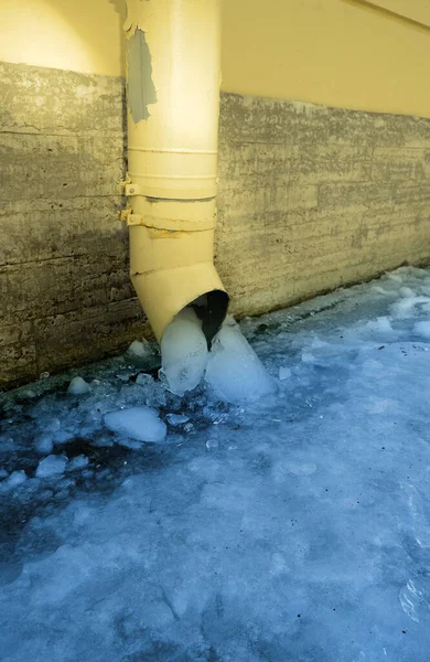 The bottom of a yellow drainpipe with ice — Stock Photo, Image