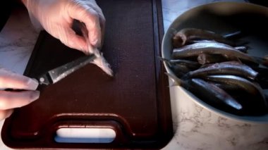 Eldivenli erkek eller balıkları fırçalıyor.