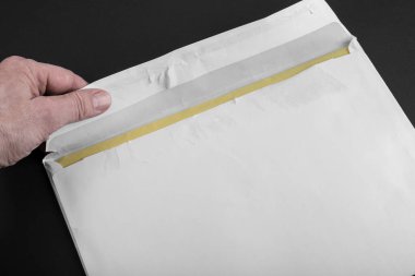 Bir adam siyah arka planda beyaz bir zarf açıyor.