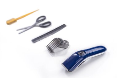 Beyaz arka planda saç kesim makinesi ve aksesuarlar