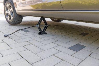 Makas kriko ile kaldırılmış bir araba. Ön ve arka tekerler değişecek.