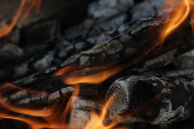 Yanmış odunlar yakın çekim ateşinde yanmış. Atmosferik arka plan ve kamp ateşi. İçeriden kopyalanmış şenlik ateşinin tasavvur edilemez detaylı görüntüsü. Duman fırtınası ve parlayan közler..