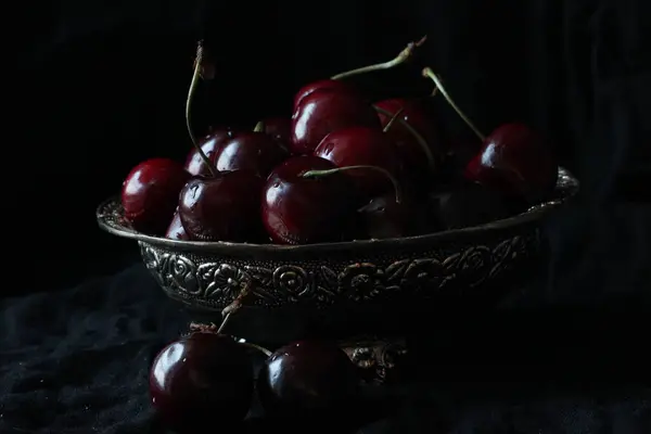 Cerezas frescas dulces maduras en plato rústico sobre fondo negro. De cerca.. — Foto de Stock