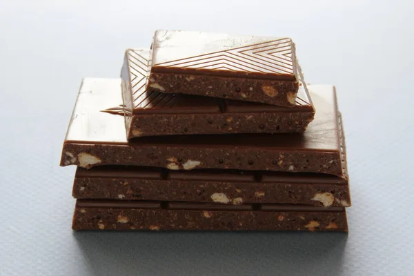 Milk chocolate pieces isolated on blue background from top view. Close up a chocolate bar isolated on blue background.