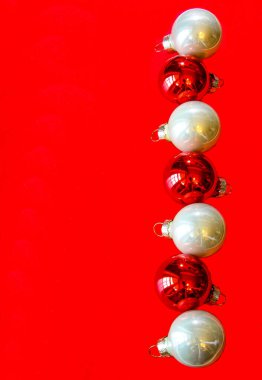 Kırmızı arka planda beyaz ve kırmızı şenlik topları olan Noel kompozisyonu, kopyalama alanı. Noel yaratıcı düzüşme, şenlikli süsler konsepti. Üst görünüm.