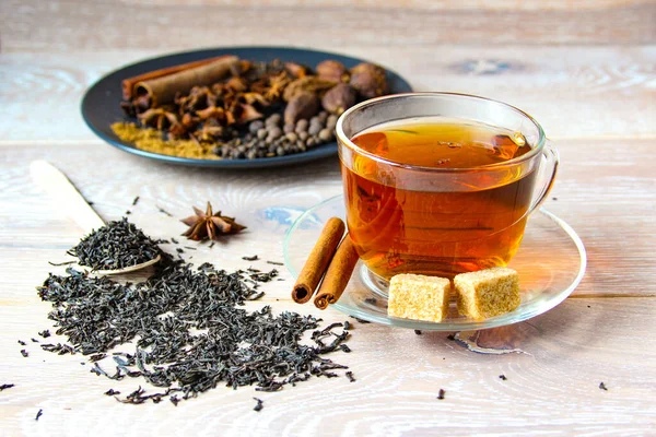 Preparation stage masala tea in a glass cup with sugar and spices.